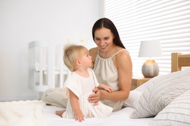 Photo of Mother and her cute little baby on bed in room