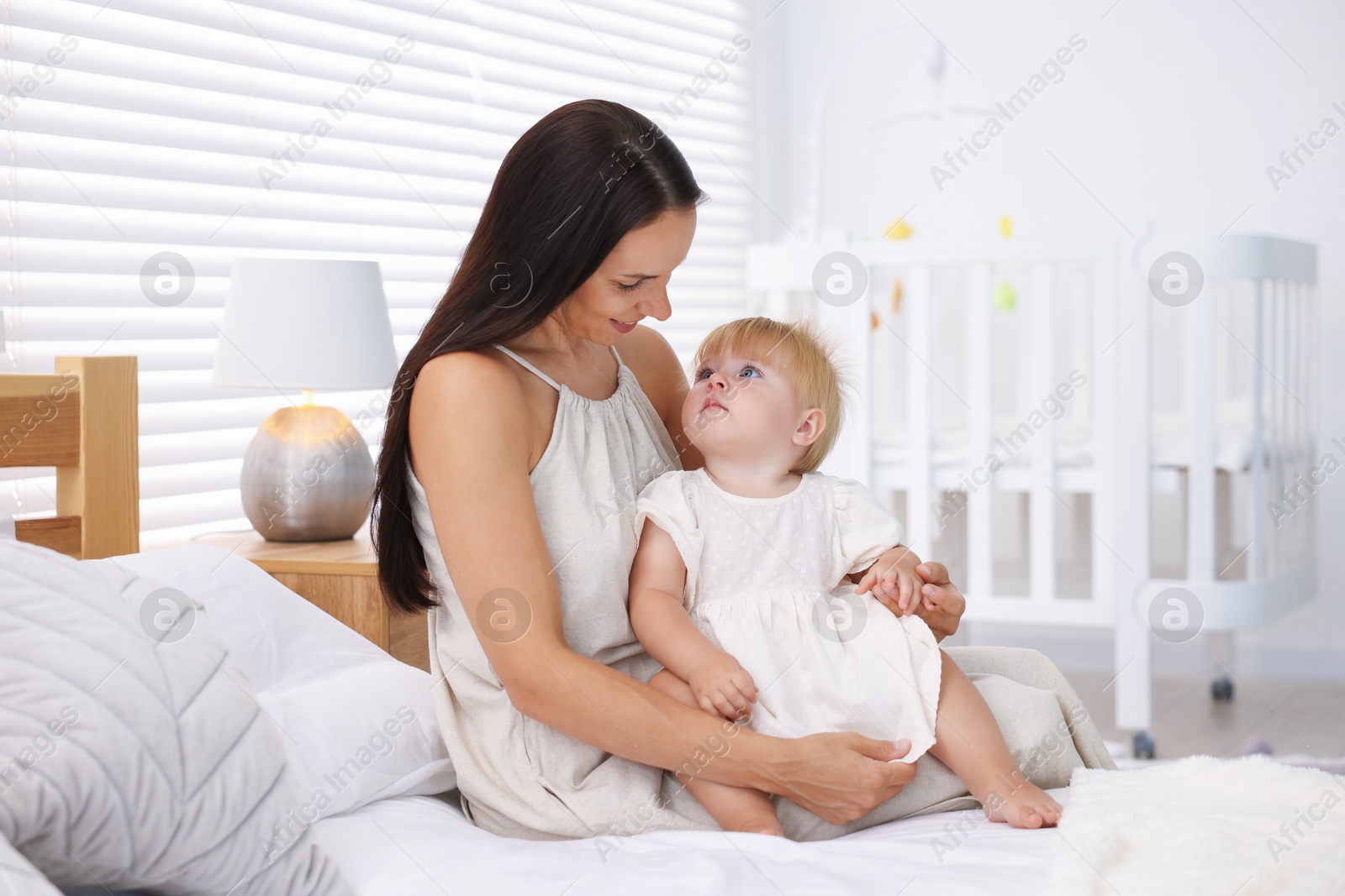 Mother and her cute little baby on bed in room Photo of Mother and her cute little baby on bed in room