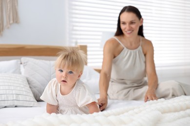 Photo of Mother and her cute little baby on bed in room, selective focus