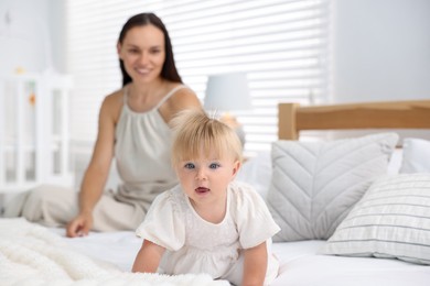 Photo of Mother and her cute little baby on bed in room, selective focus