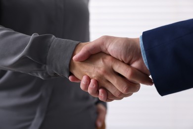 Photo of Business partners shaking hands indoors, closeup view