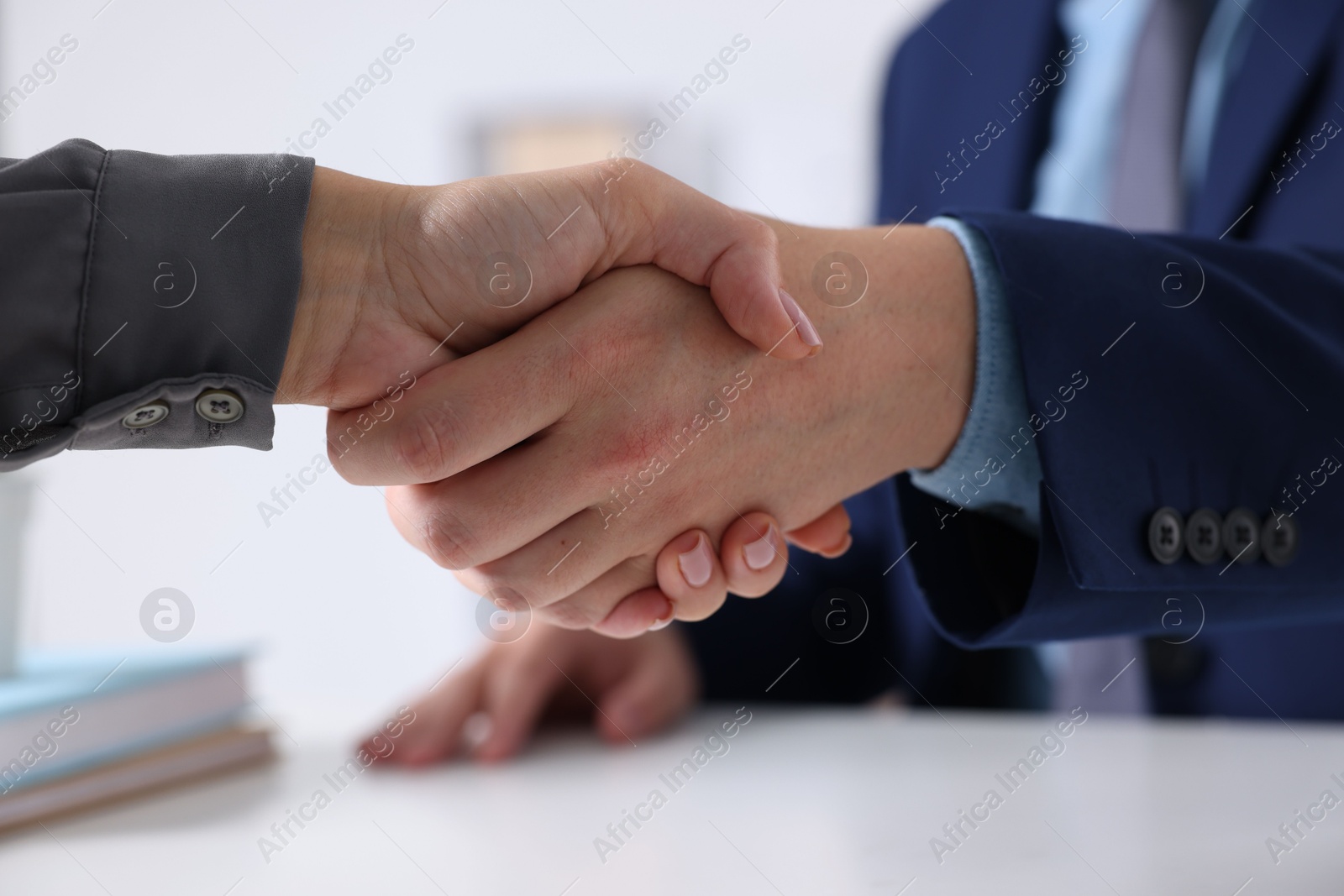 Photo of Business partners shaking hands at table indoors, closeup