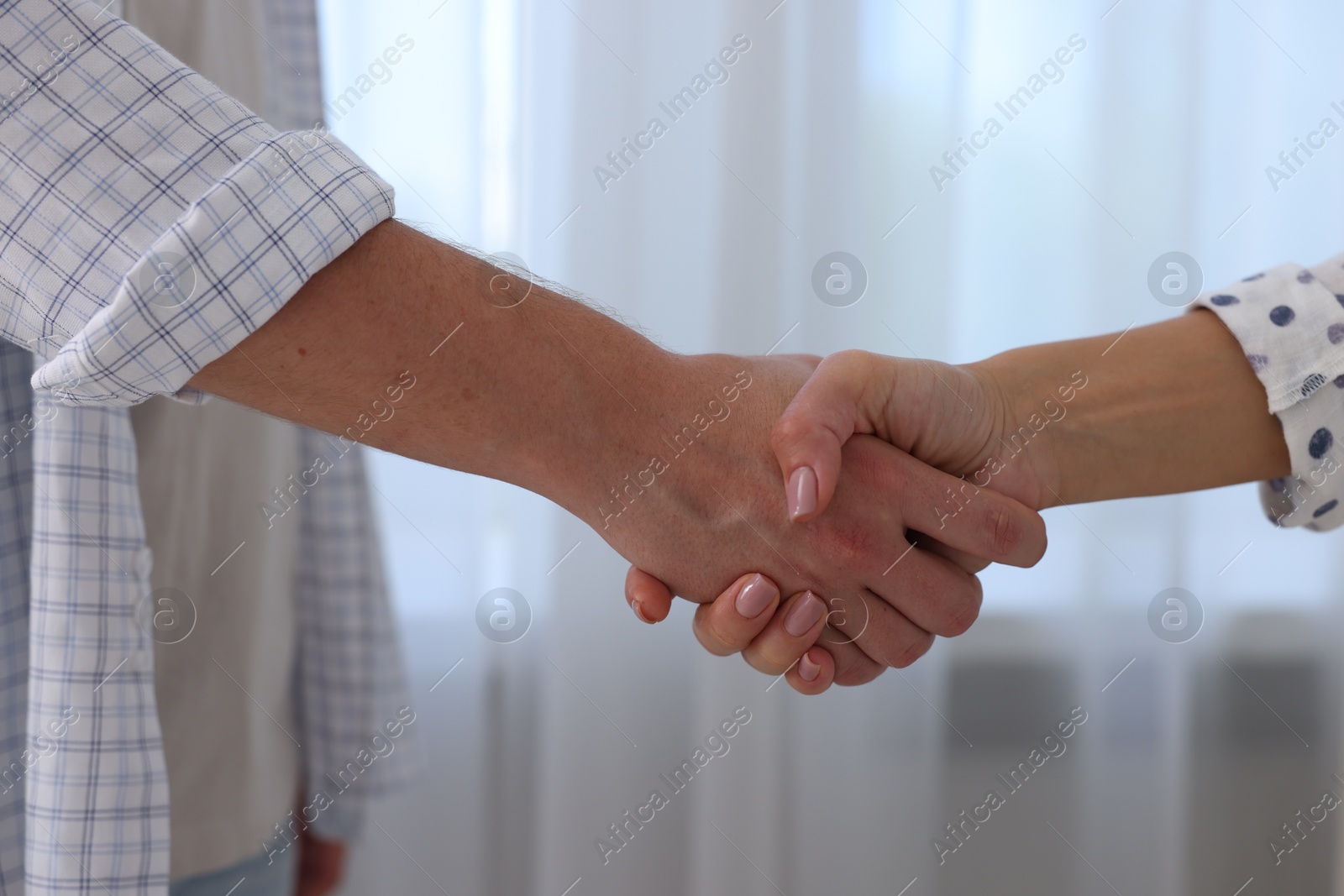 Photo of Man and woman shaking hands indoors, closeup