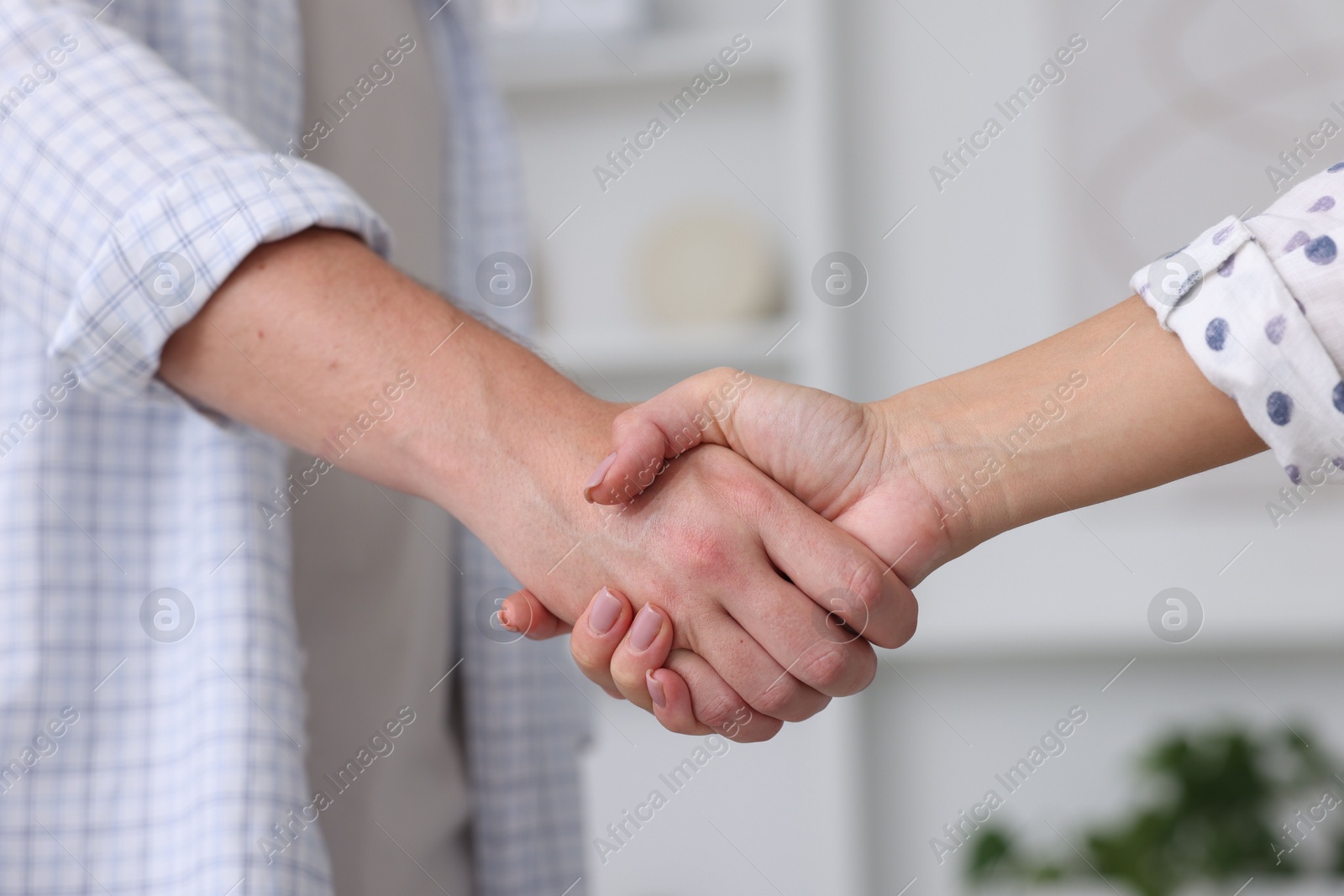 Photo of Man and woman shaking hands indoors, closeup