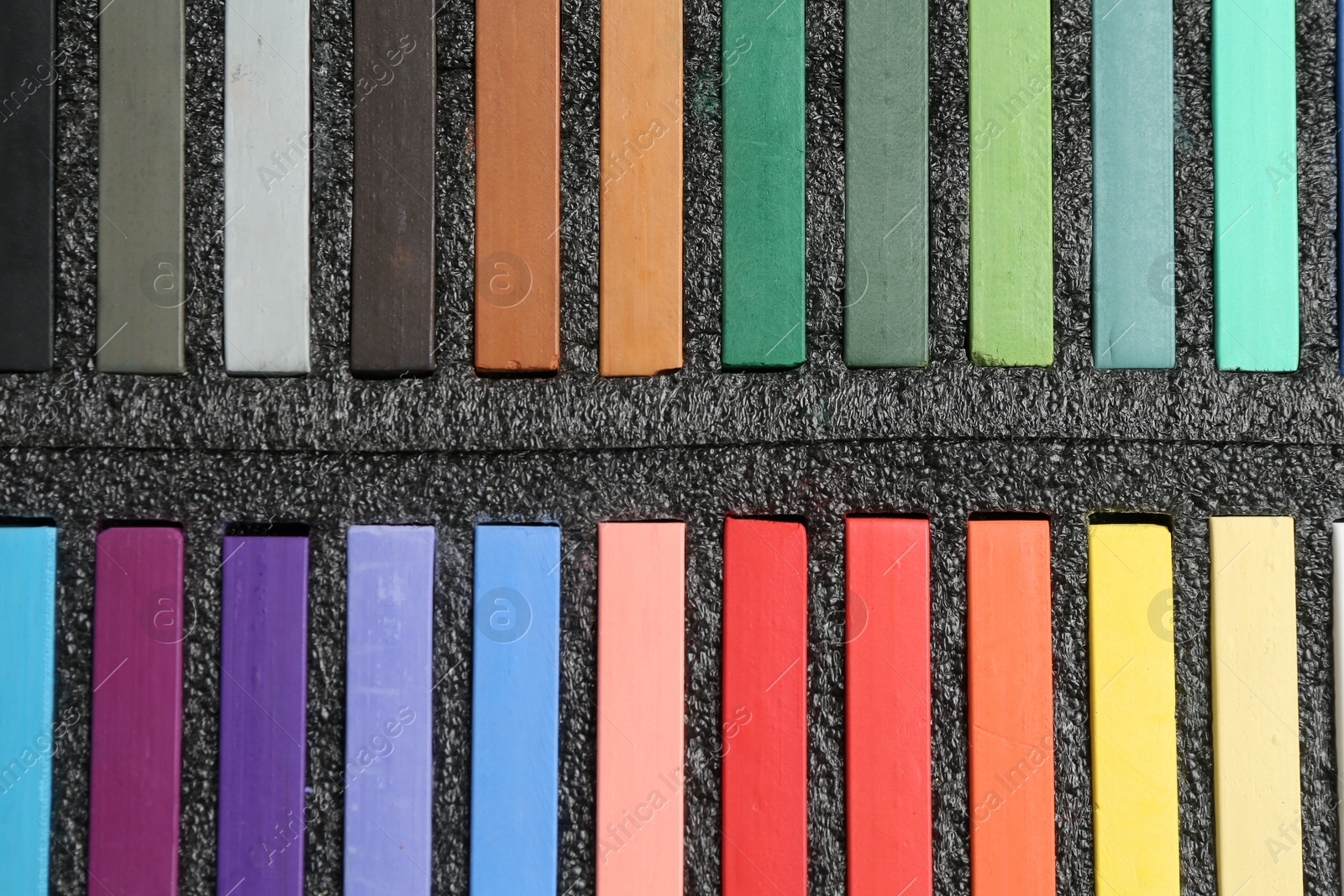 Photo of Colorful chalk pastels in box, top view