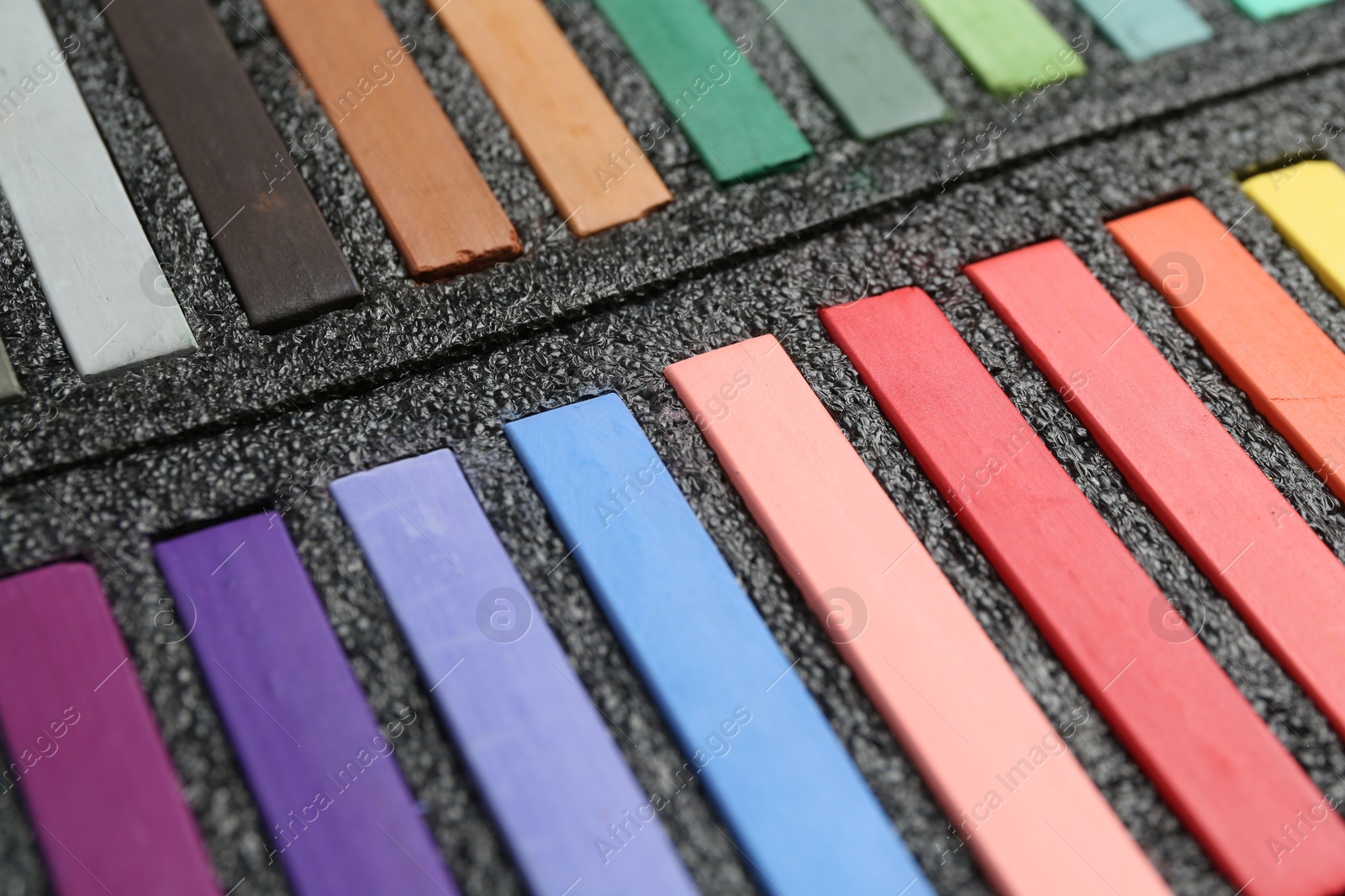 Photo of Set of colorful chalk pastels in box, closeup