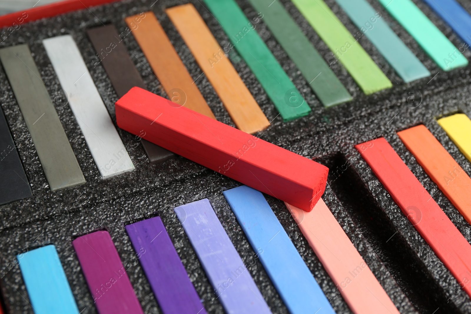 Photo of Set of colorful chalk pastels in box, closeup