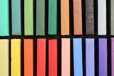 Photo of Colorful chalk pastels on black table, top view