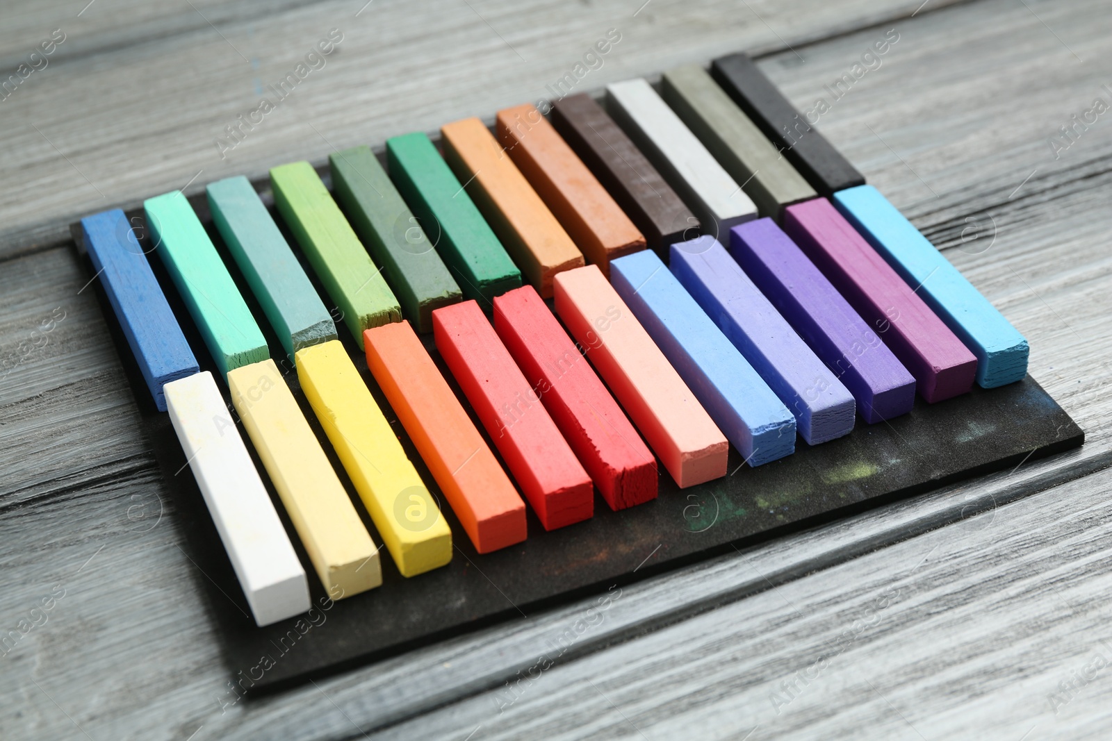 Photo of Colorful chalk pastels on wooden table, closeup