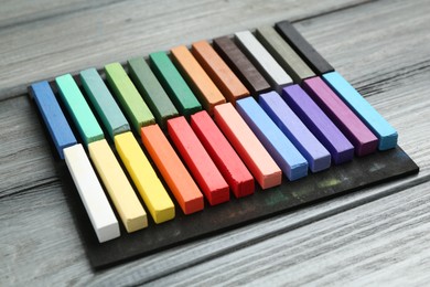 Photo of Colorful chalk pastels on wooden table, closeup