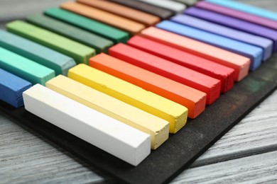 Photo of Colorful chalk pastels on wooden table, closeup