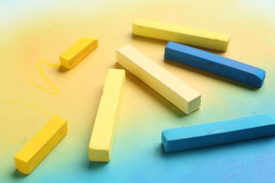 Photo of Yellow and light blue chalk pastels on color background, closeup