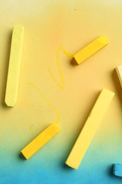 Photo of Yellow chalk pastels on color background, top view