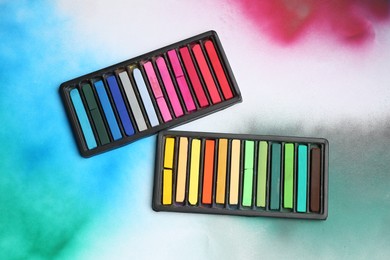 Photo of Colorful chalk pastels in trays on color background, flat lay