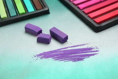 Photo of Colorful chalk pastels in trays on color background, closeup