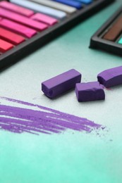 Photo of Colorful chalk pastels in trays on color background, closeup