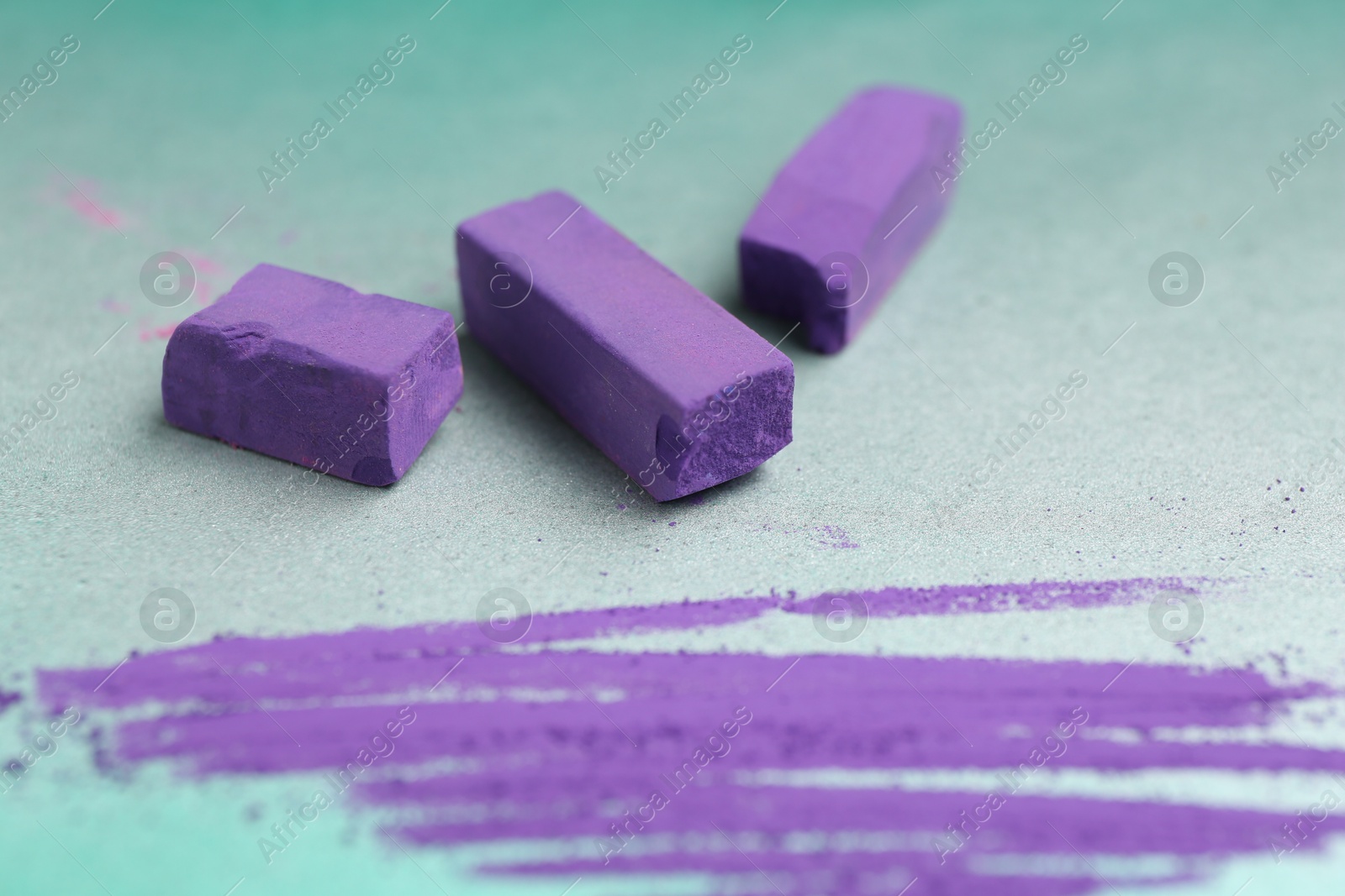 Photo of Violet chalk pastels and scribble on color background, closeup