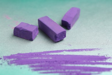 Photo of Violet chalk pastels and scribble on color background, closeup
