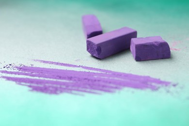 Photo of Violet chalk pastels and scribble on color background, closeup