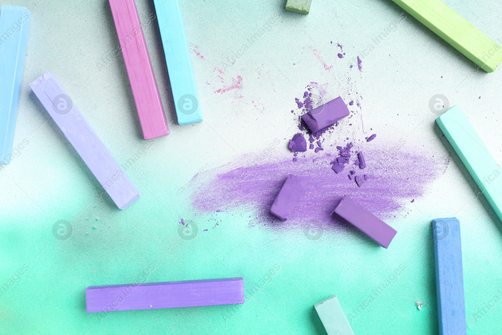 Photo of Colorful chalk pastels on color background, flat lay