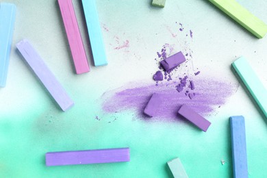 Photo of Colorful chalk pastels on color background, flat lay