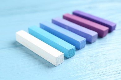 Photo of Colorful chalk pastels on light wooden table, closeup
