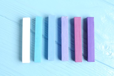 Photo of Colorful chalk pastels on light wooden table, flat lay