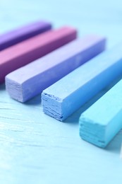 Photo of Colorful chalk pastels on light wooden table, closeup