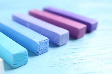 Photo of Colorful chalk pastels on light wooden table, closeup
