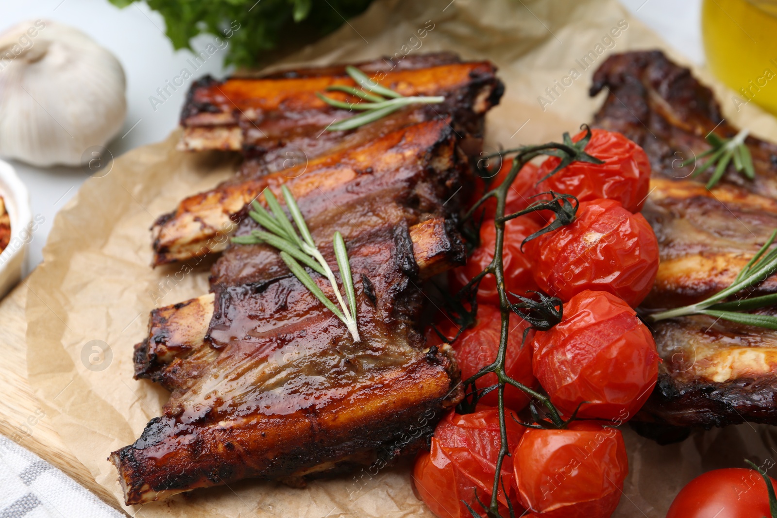 Roasted beef ribs with rosemary and tomatoes on table, closeup Photo of Roasted beef ribs with rosemary and tomatoes on table, closeup