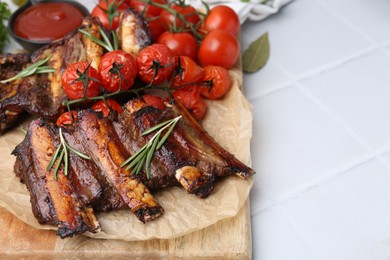 Photo of Roasted beef ribs with rosemary, tomatoes and sauce on white tiled table, closeup