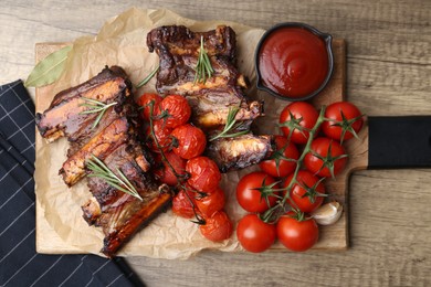 Photo of Roasted beef ribs with rosemary, tomatoes and sauce on wooden table, top view