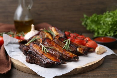 Photo of Roasted beef ribs with spices and tomatoes on wooden table, closeup