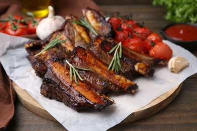 Photo of Roasted beef ribs with spices and tomatoes on wooden table, closeup