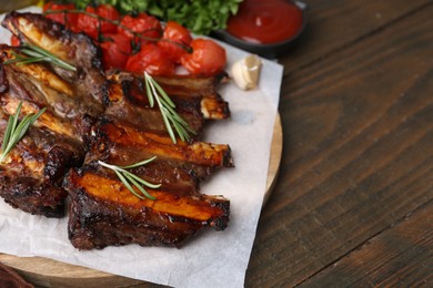 Photo of Roasted beef ribs with spices, tomatoes and tomato sauce on wooden table, closeup