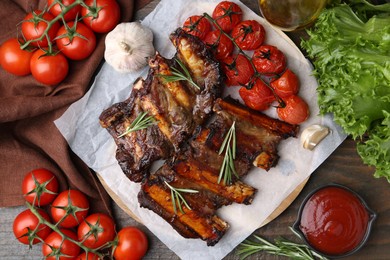 Photo of Roasted beef ribs with spices, tomatoes and tomato sauce on wooden table, flat lay