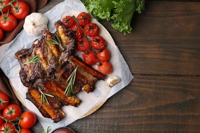 Photo of Roasted beef ribs with spices and tomatoes on wooden table, flat lay. Space for text