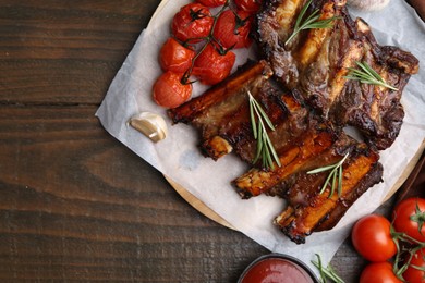 Photo of Roasted beef ribs with spices and tomatoes on wooden table, flat lay. Space for text