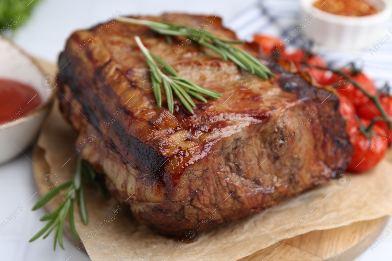 Delicious roast beef with rosemary and tomatoes on table, closeup Photo of Delicious roast beef with rosemary and tomatoes on table, closeup