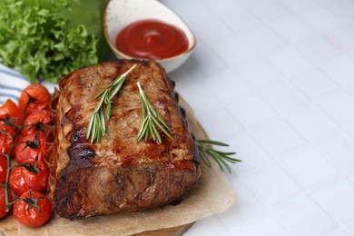 Photo of Delicious roast beef with rosemary, tomatoes, sauce and lettuce on white tiled table, closeup. Space for text