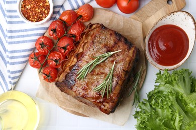 Photo of Delicious roast beef with rosemary, tomatoes and other products on table, flat lay