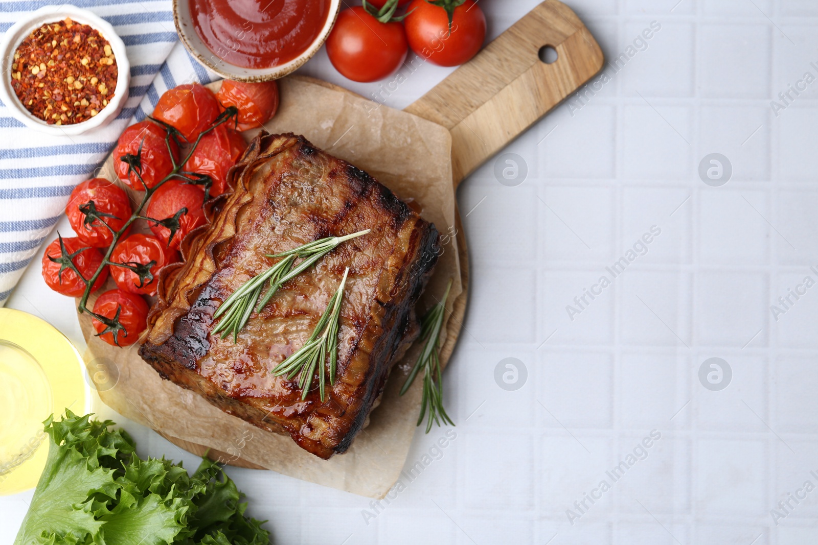 Delicious roast beef with rosemary, tomatoes and other products on white tiled table, flat lay. Space for text Photo of Delicious roast beef with rosemary, tomatoes and other products on white tiled table, flat lay. Space for text