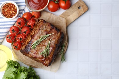 Photo of Delicious roast beef with rosemary, tomatoes and other products on white tiled table, flat lay. Space for text