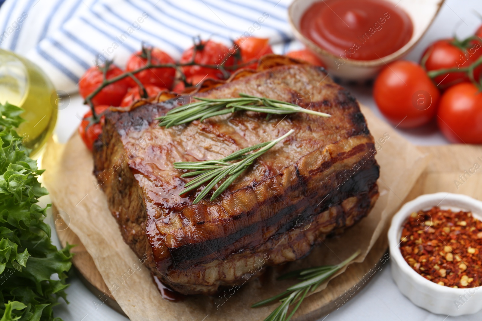 Delicious roast beef with rosemary, tomatoes and other products on table, closeup Photo of Delicious roast beef with rosemary, tomatoes and other products on table, closeup
