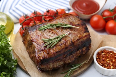 Photo of Delicious roast beef with rosemary, tomatoes and other products on table, closeup