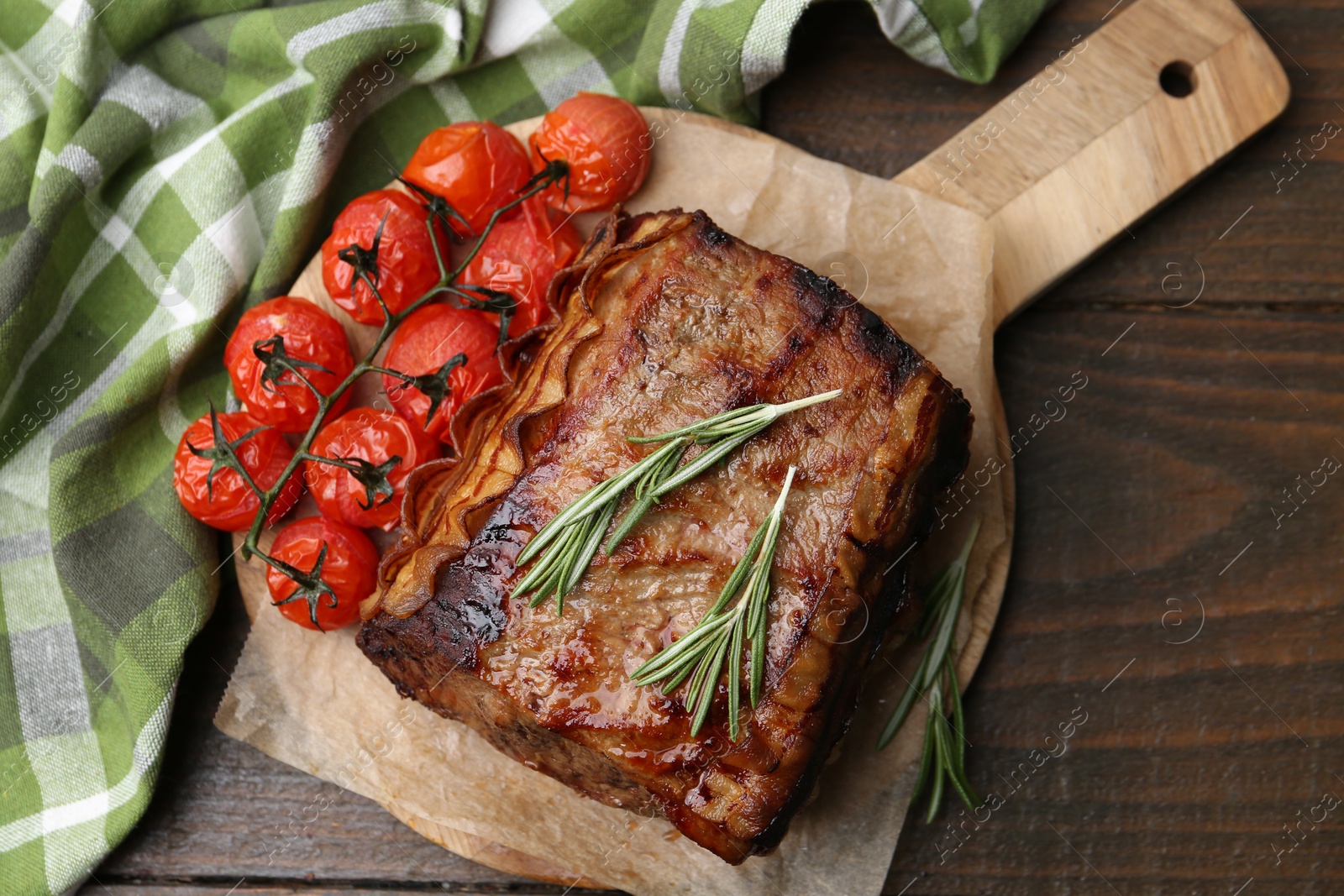 Delicious roast beef with rosemary and tomatoes on wooden table, top view Photo of Delicious roast beef with rosemary and tomatoes on wooden table, top view