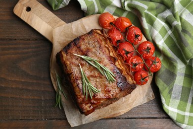 Photo of Delicious roast beef with rosemary and tomatoes on wooden table, top view