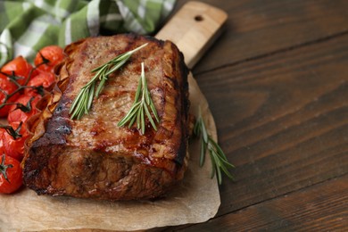 Photo of Delicious roast beef with rosemary and tomatoes on wooden table, closeup. Space for text