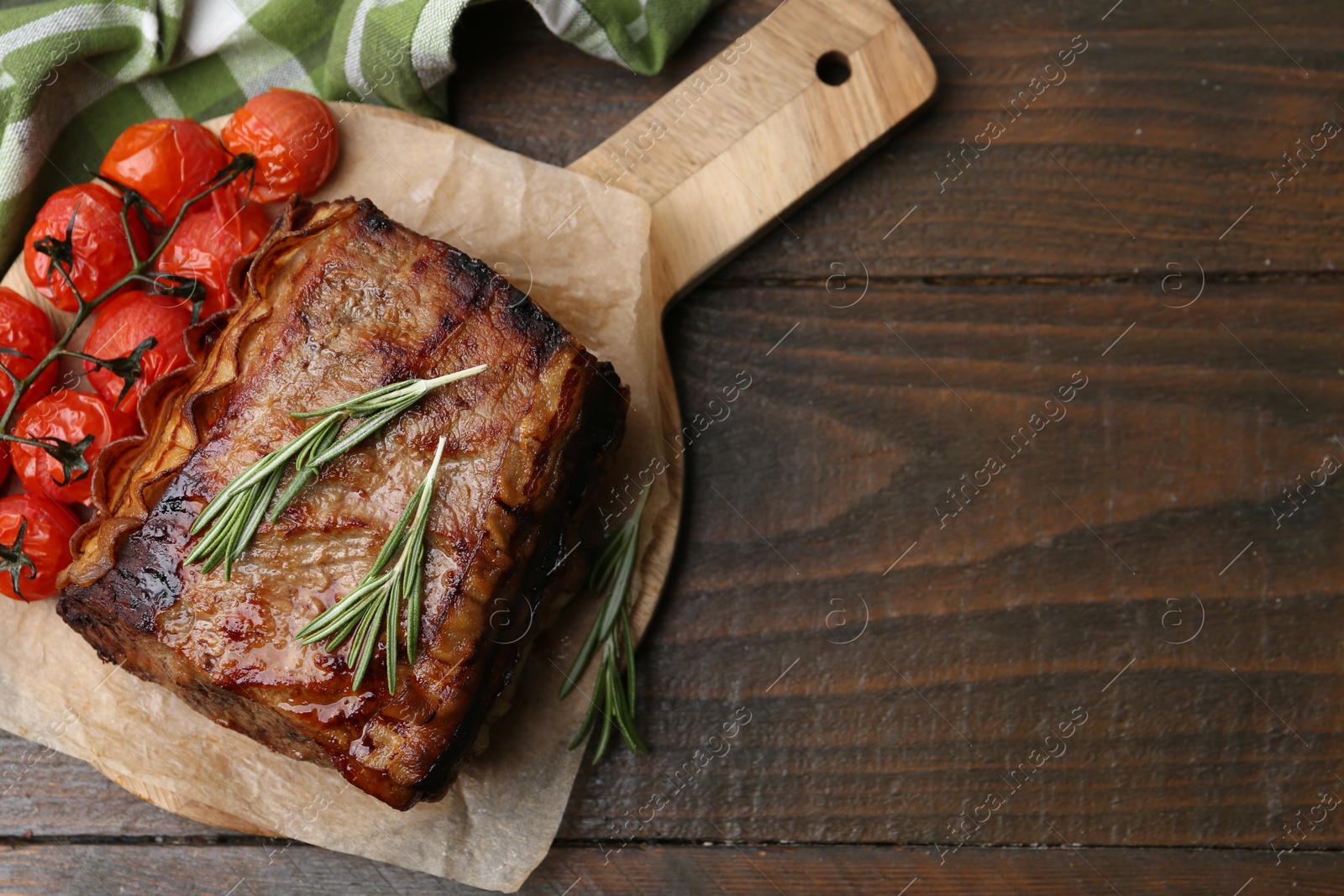 Delicious roast beef with rosemary and tomatoes on wooden table, top view. Space for text Photo of Delicious roast beef with rosemary and tomatoes on wooden table, top view. Space for text