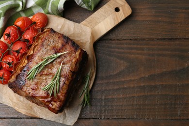 Photo of Delicious roast beef with rosemary and tomatoes on wooden table, top view. Space for text